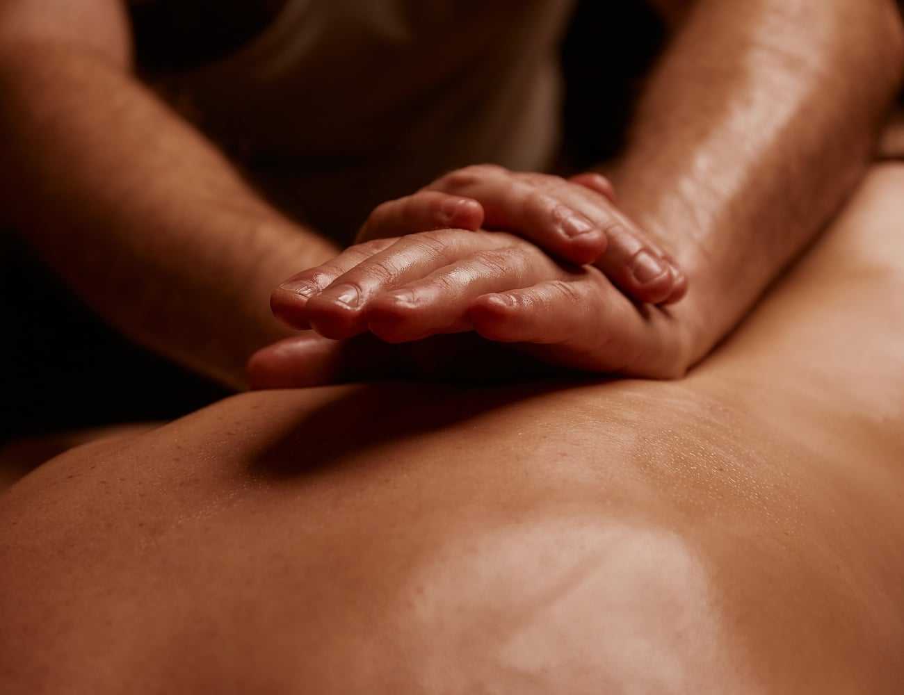 Hands applying gentle pressure during a back massage, emphasizing relaxation and care.
